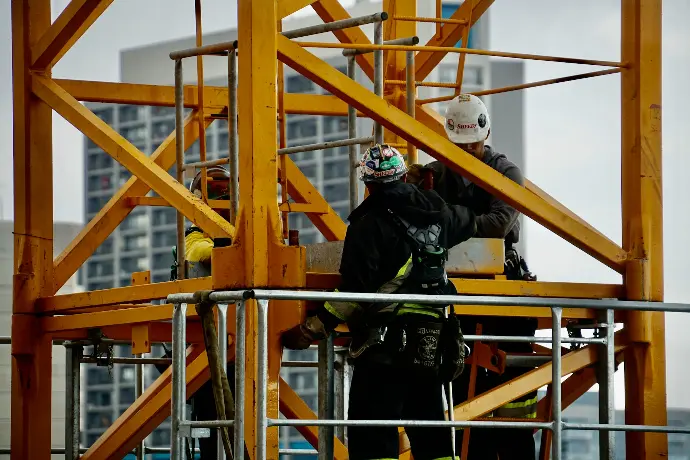 man in black jacket and helmet climbing orange ladder